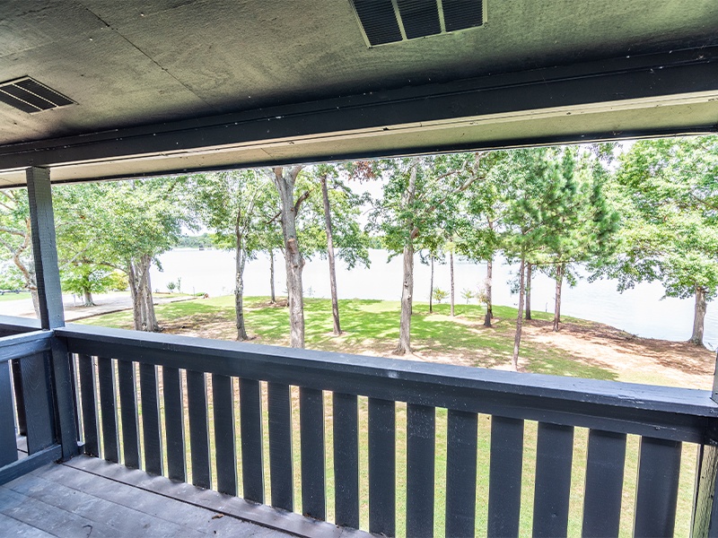 A balcony with a view of a grassy area and trees.